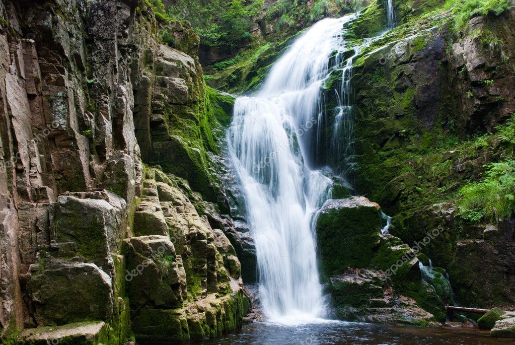 Helicopter landed beside a waterfall and clear river in native forest