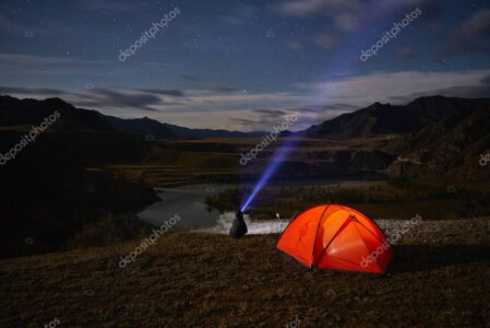 Simple riverside fly fishing camp with tent beside a clear stream