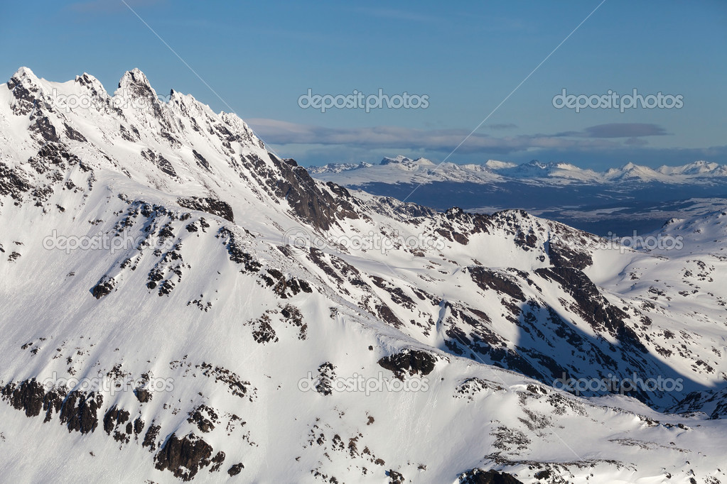 Couple standing in the snow beside a helicopter high in the mountains