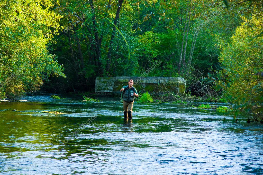 Guide helping a guest with a fly cast beside a small stream