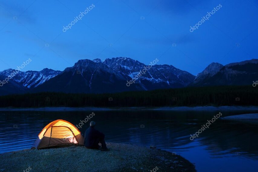 Riverside fly fishing camp with tent and camp chairs at golden hour.
