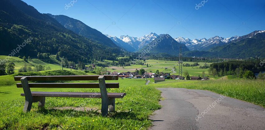 Guests sitting on a rock outcrop looking over a wide landscape of lakes and peaks.