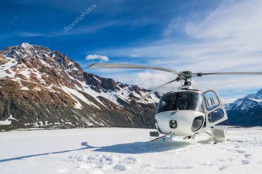 Helicopter landed on a snowy ridge with wide views over surrounding peaks.
