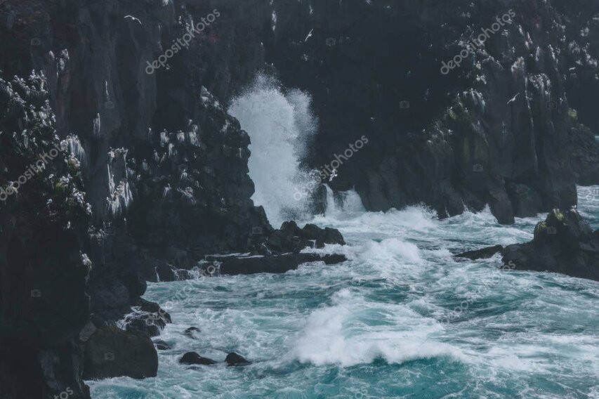 Remote coastal cliffs and surf seen from a helicopter window.