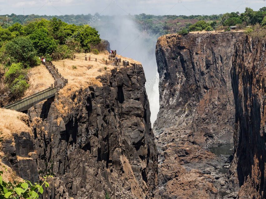 Helicopter near a tall waterfall dropping into a remote valley.