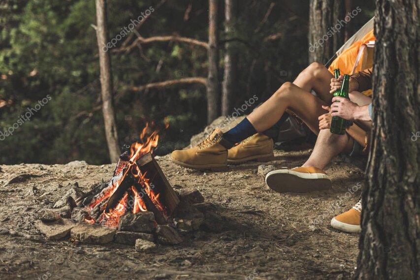 Guests sitting around a small campfire at dusk sharing stories.