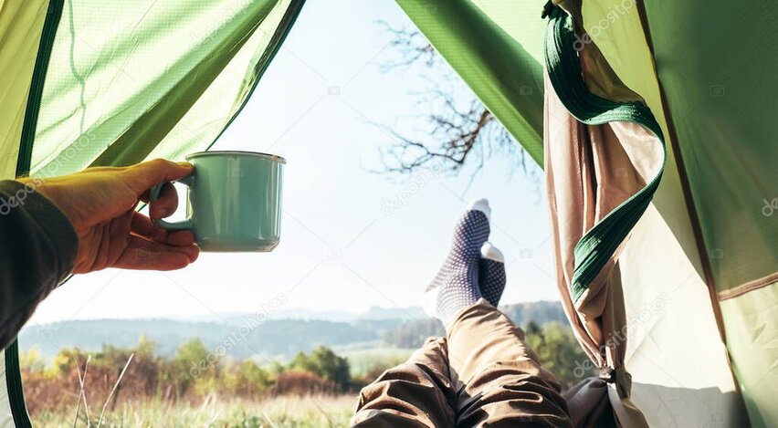 Guest holding a steaming mug of coffee outside a tent on a cool morning.