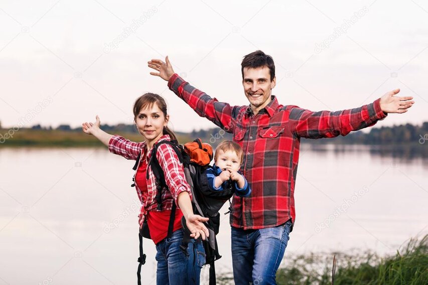 Family group smiling on a forest trail with daypacks on.