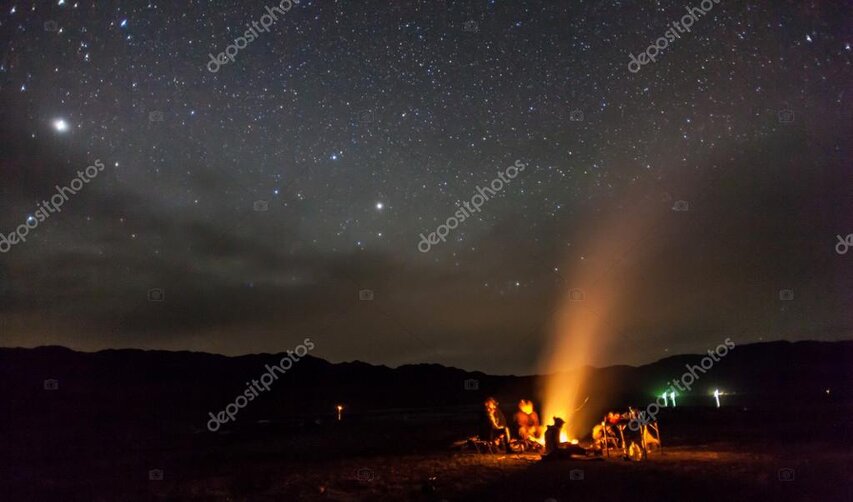 Tents and campfire glowing under a starry sky in remote New Zealand backcountry